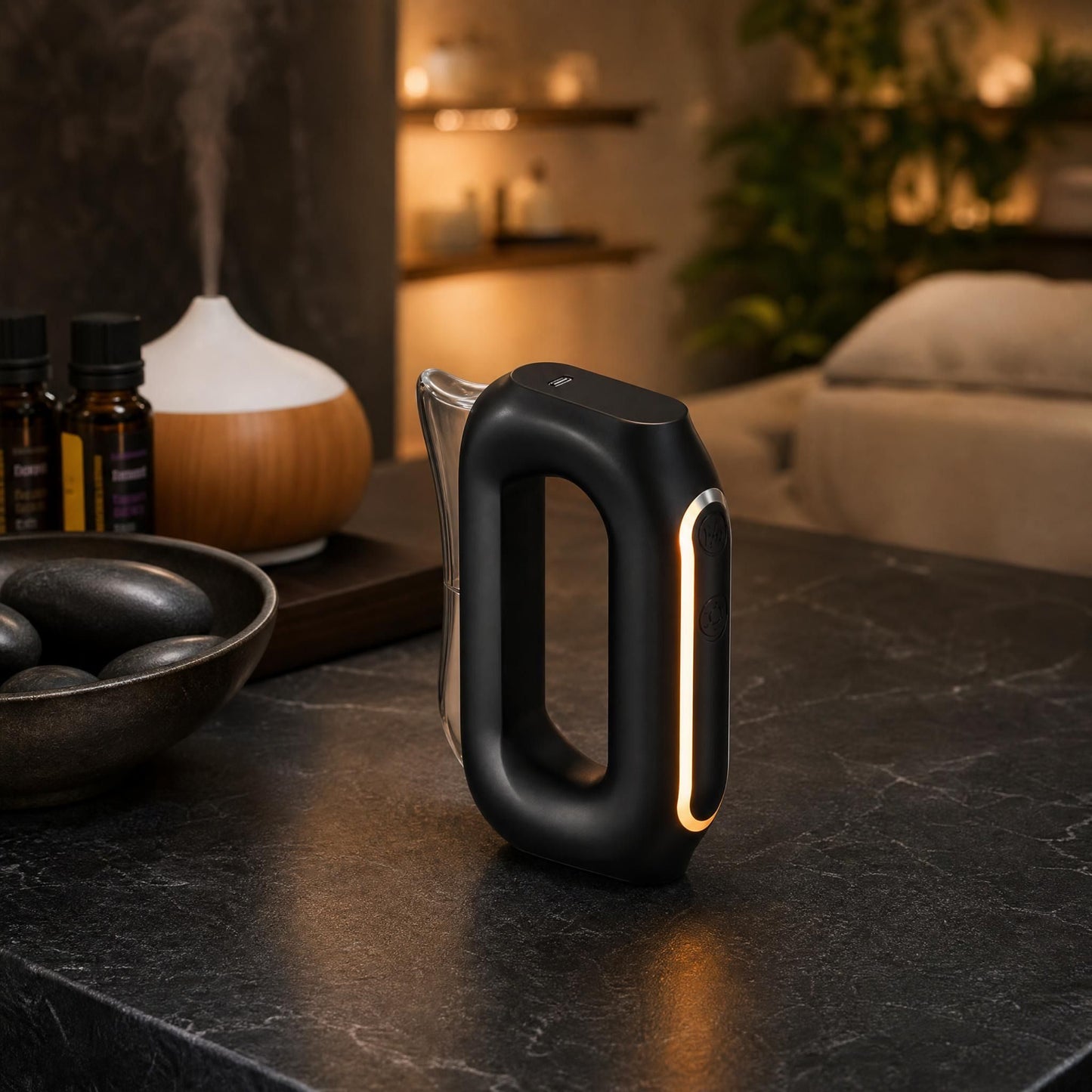 Massager on black counter with stones and diffuser, in a cozy wellness space with warm, soft lighting.