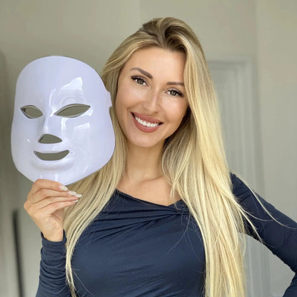 LED skincare mask for wrinkle reduction held by a smiling woman with long blonde hair. Ideal for skin rejuvenation and texture improvement.