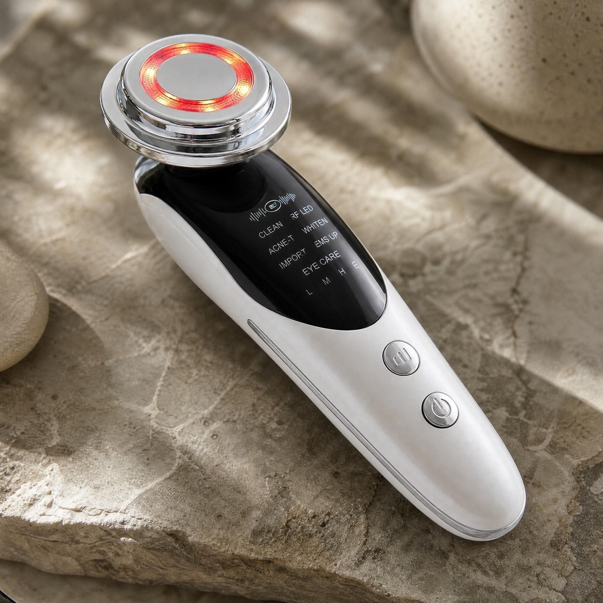 Close-up of the light therapy panels and microcurrent contacts on the 7 in 1 Face Lift Facial Massager on a textured stone surface.