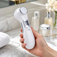 Close-up of the 6-in-1 beauty device in a model's hand, showing its ergonomic design and smooth matte finish against a modern bathroom background.