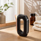 Close-up of heated microcurrent gua sha massager resting on a wooden surface with a warm glow, highlighting its ergonomic curved design.