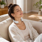 Model wearing white SKG Smart Neck Massager in a bright living room with natural light.