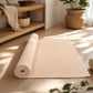 Close-up of beige natural jute yoga mat with woven fibers in a peaceful wellness setting.