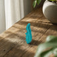 Close-up of a small ergonomic trigger point massager on a wooden surface, highlighting its contours and textured grip.