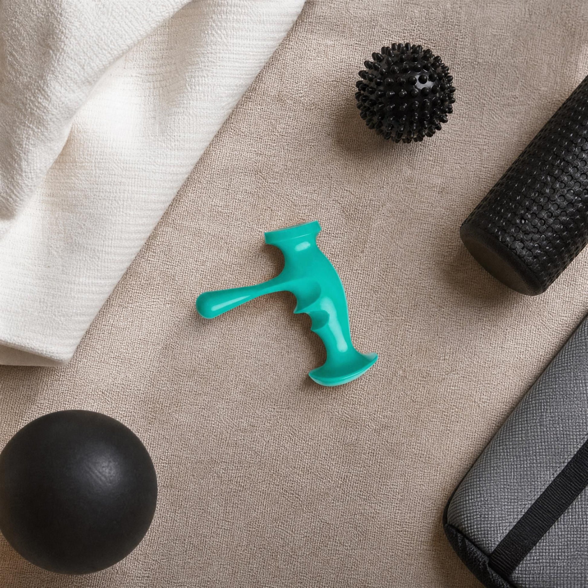 Top-down view of the trigger point massager on a fabric surface, surrounded by massage accessories in a home or therapy setting.