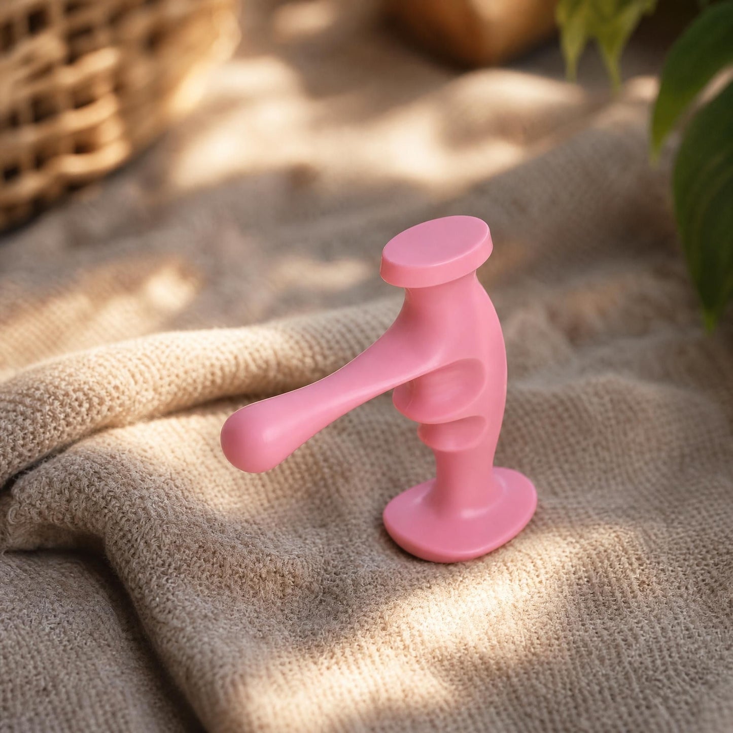 Side view of a small trigger point massager placed on textured fabric with warm sunlight, showing its ergonomic features and materials.