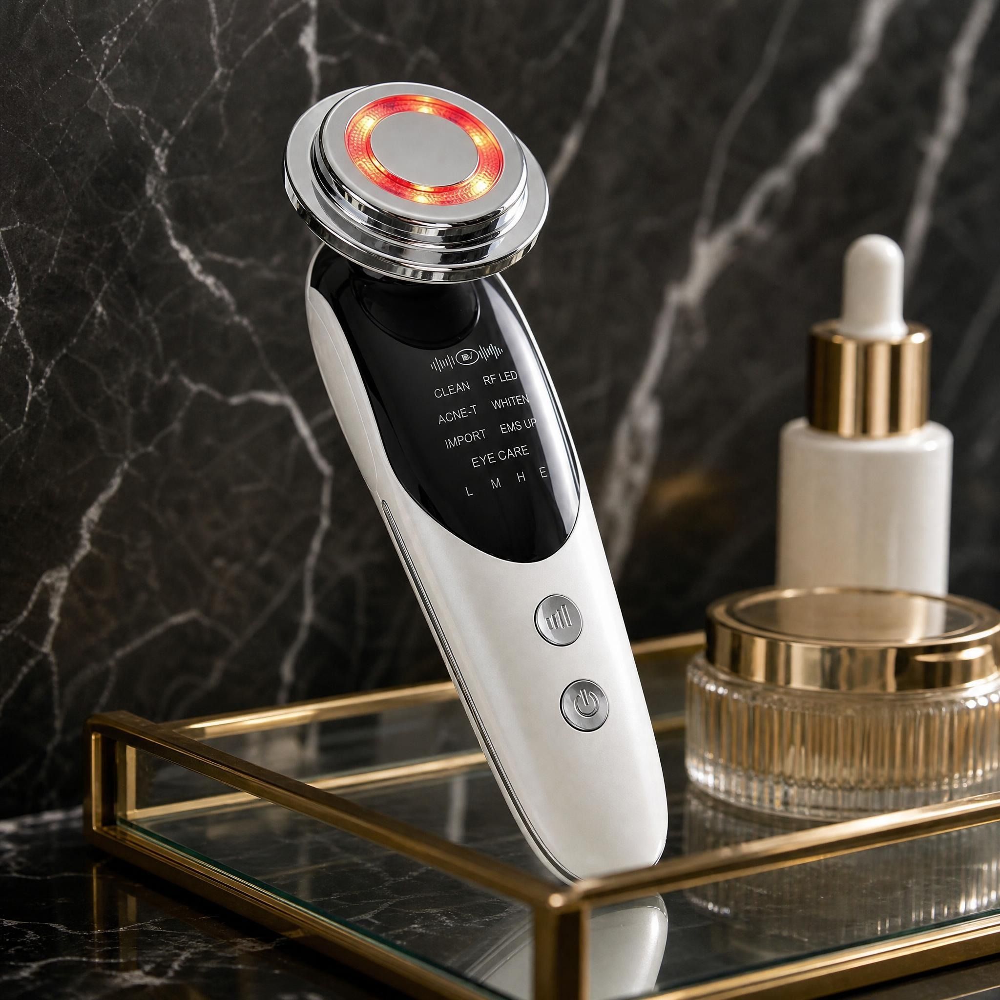 Side view of the white 7 in 1 Face Lift Facial Massager on a glass tray against a black marble backdrop with soft lighting.